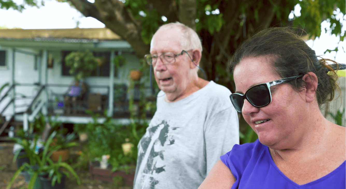 Older man standing next to a women, outside in a backyard.
